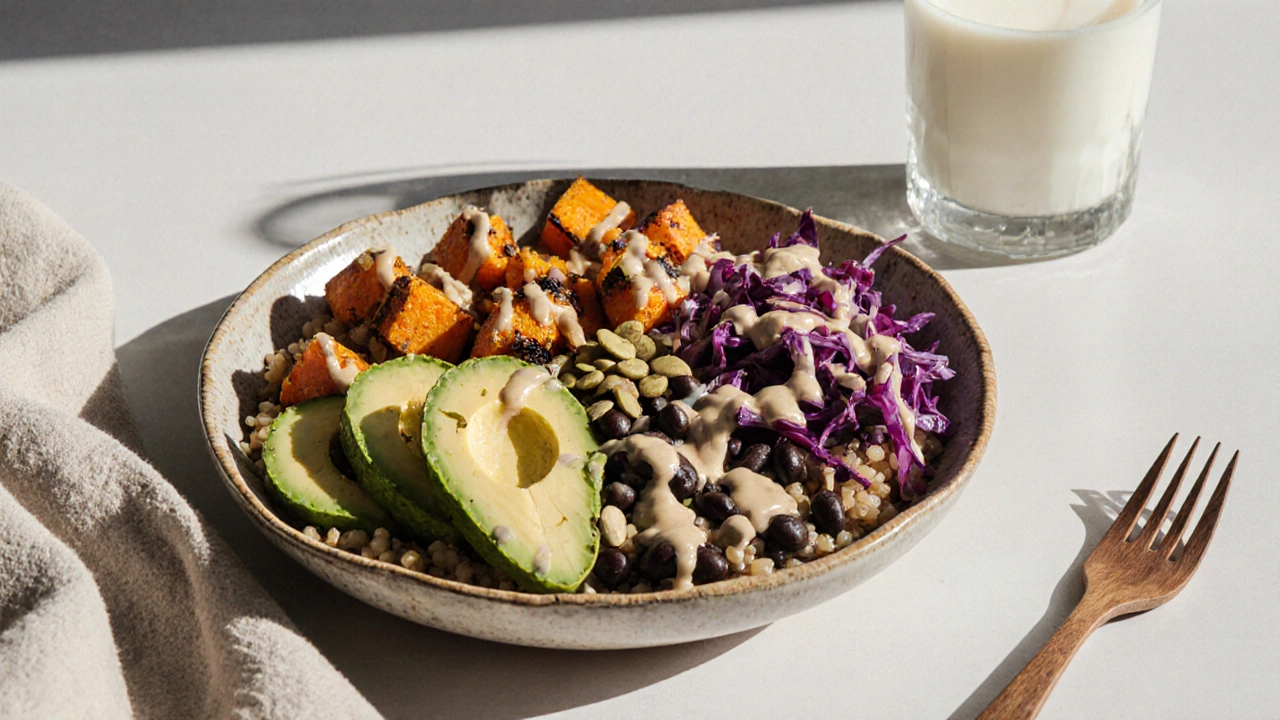 Vibrant grain bowl with sweet potato, beans, avocado, and tahini dressing on a ceramic plate.